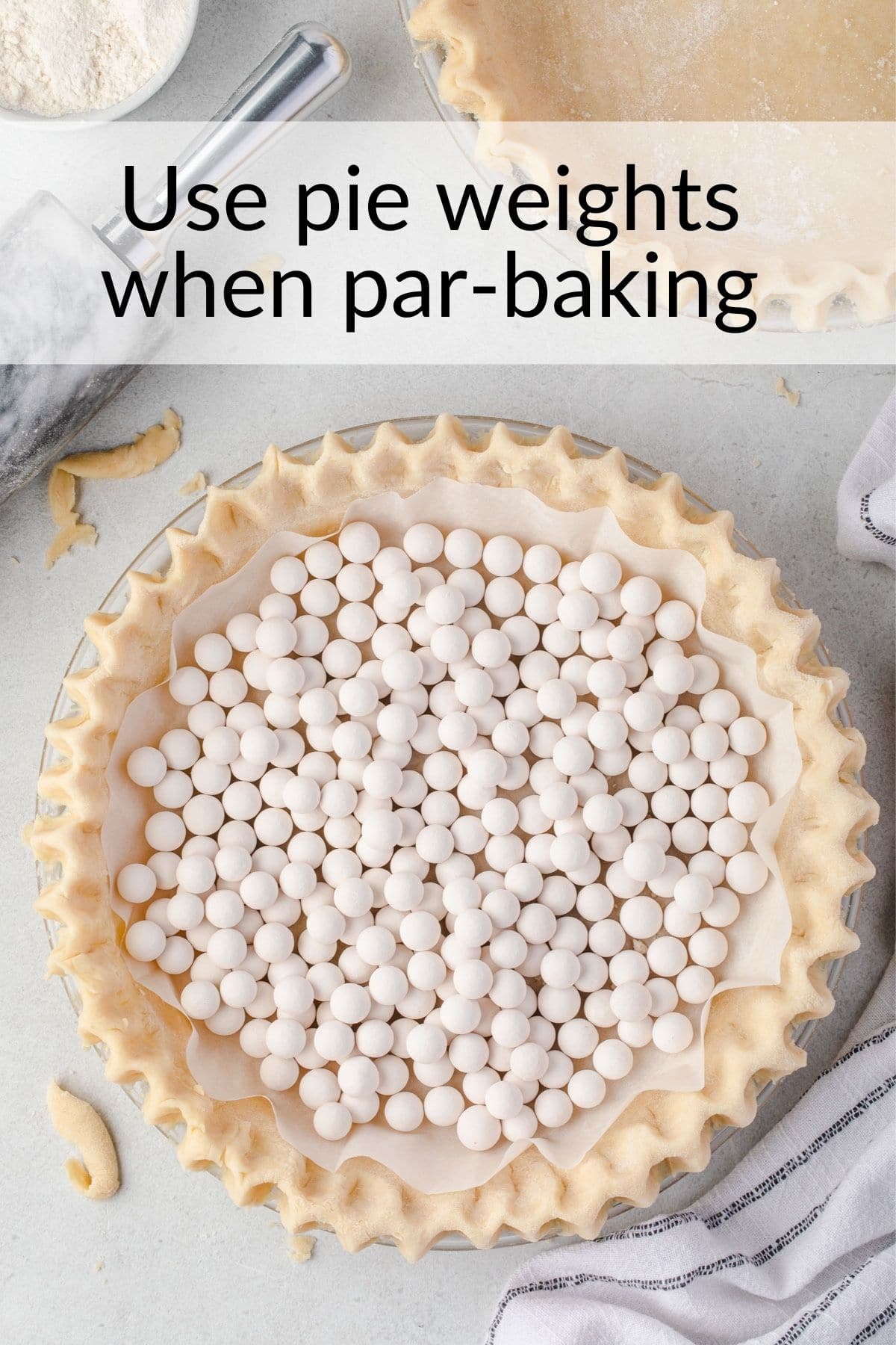 Pie crust in plate with crimped edges, parchment lining dough and pan filled with pie weights.