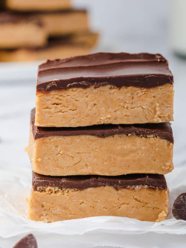 Stack of 3 no bake peanut butter buckeye bars with a plate of bars in background.