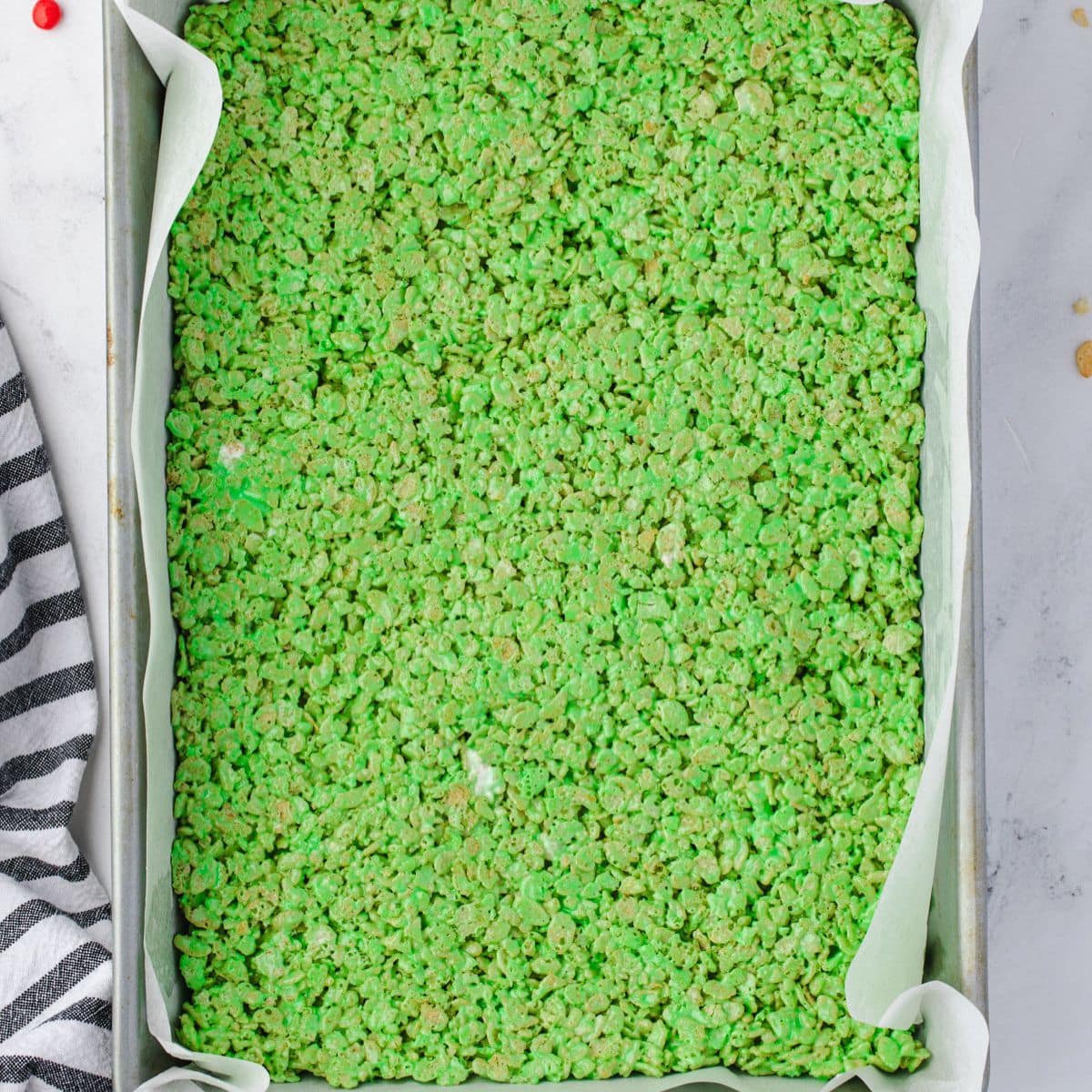 A pan of green rice crispy treats on parchment paper, seen from above.