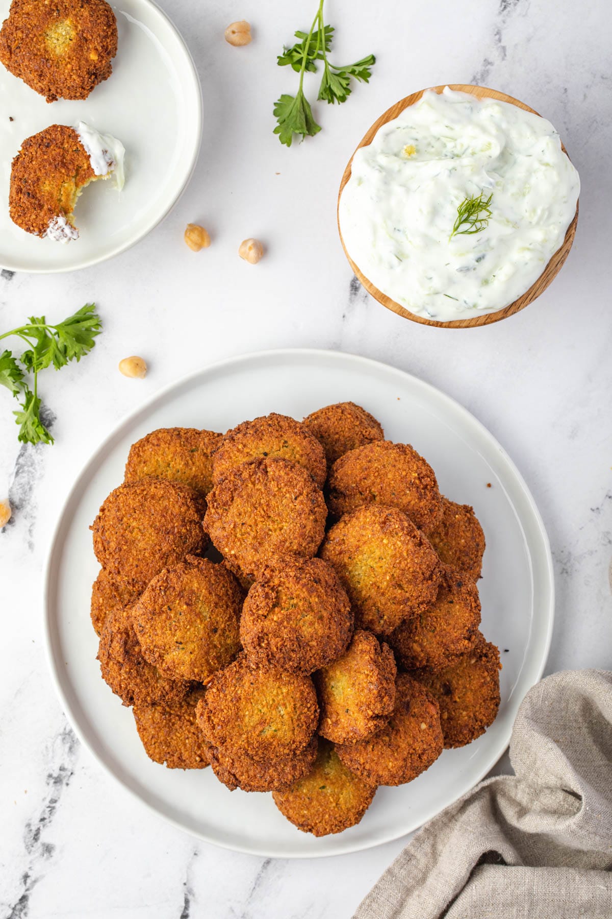 A stack of falafel on a plate with a bowl of tzatziki.