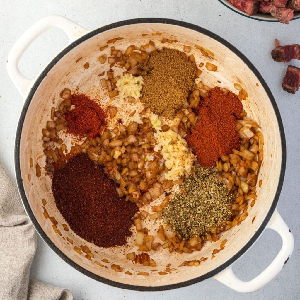 Chili spices, onion, and garlic in a dutch oven.