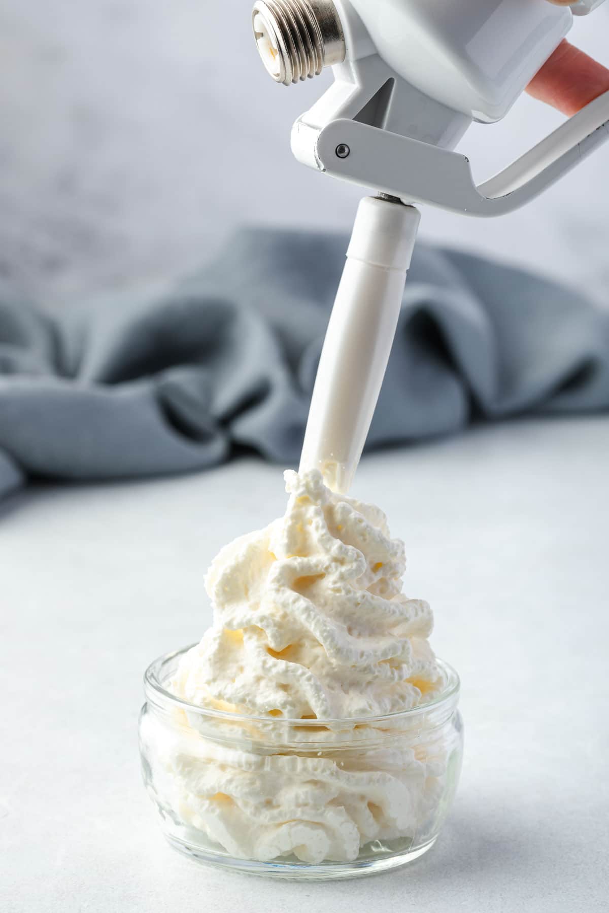 Dispensing whipped cream into a shallow jar.