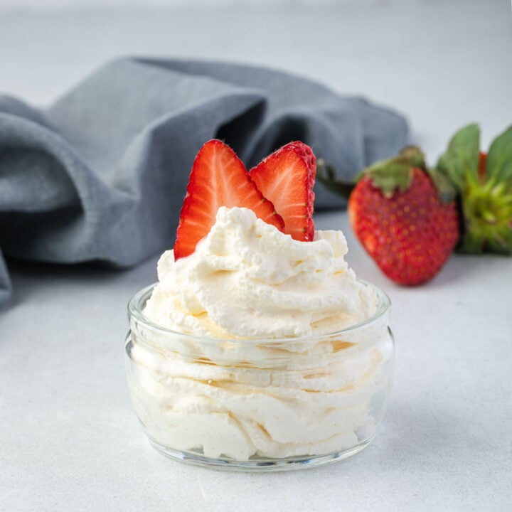 Whipped cream in a jar topped with sliced strawberries.