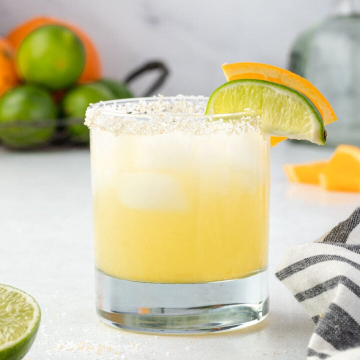 Texas margarita garnished with lime and orange wedges.
