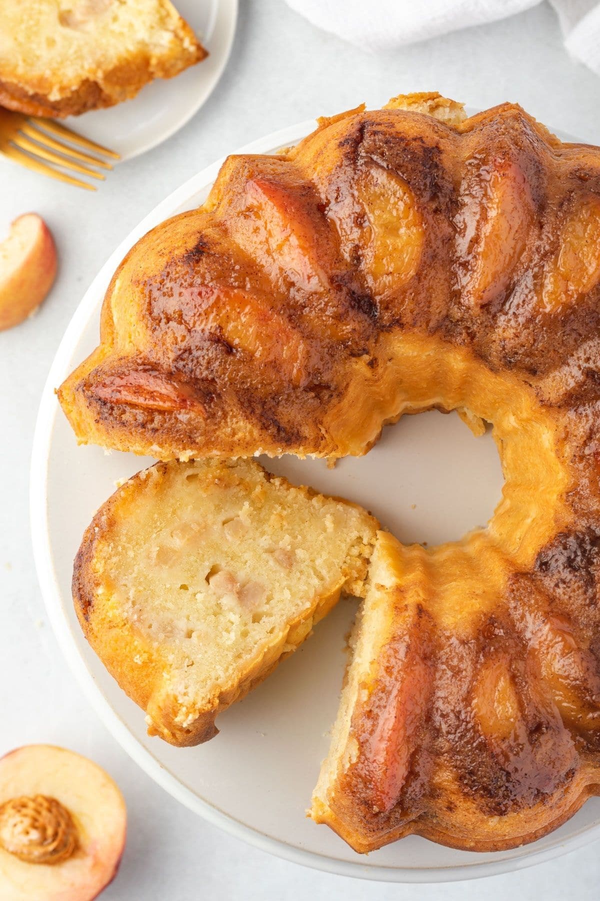 Peach bundt cake with a slice cut and laying on cake plate.