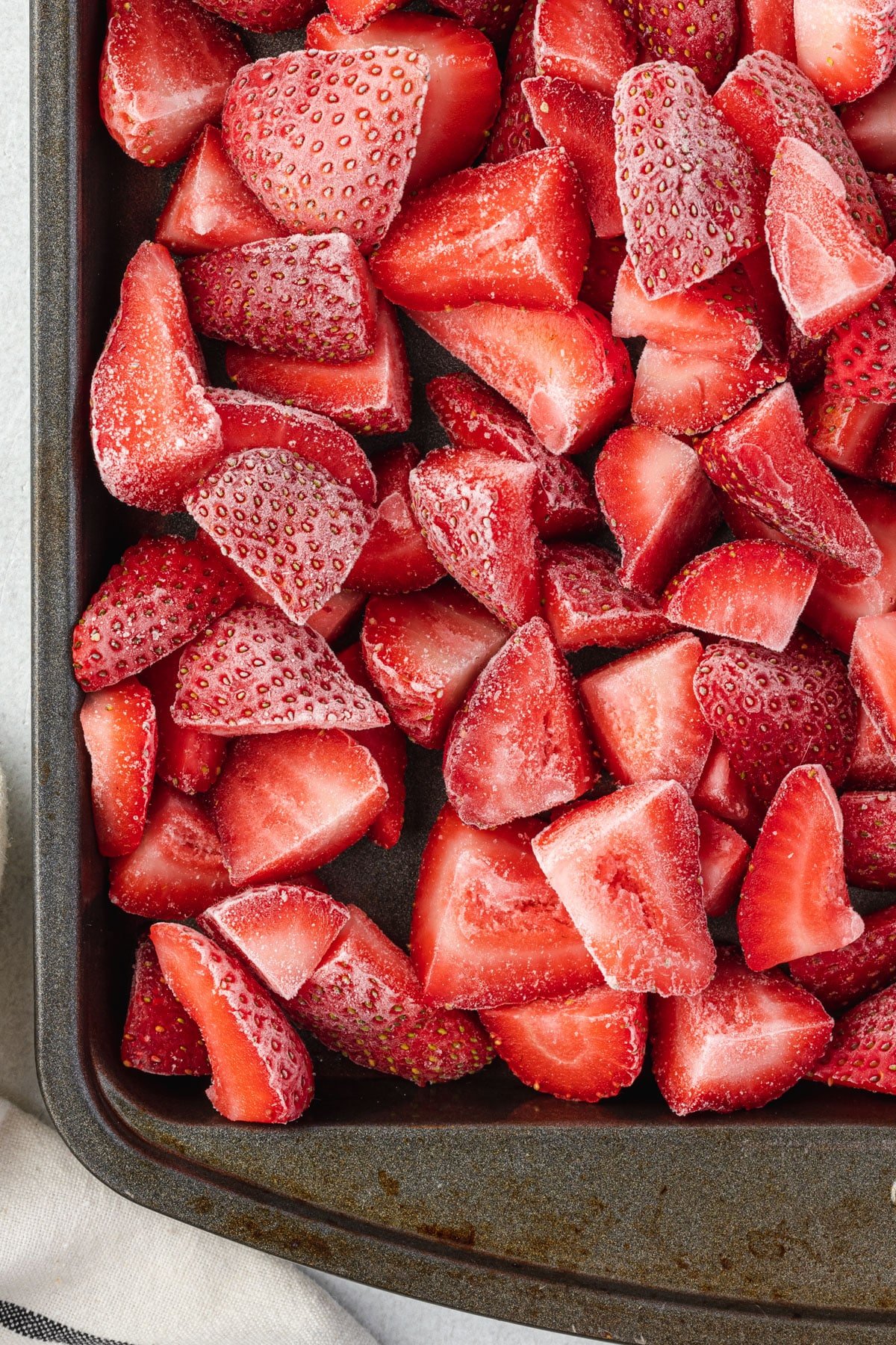 Overhead view of frozen strawberries on a cookie sheet.