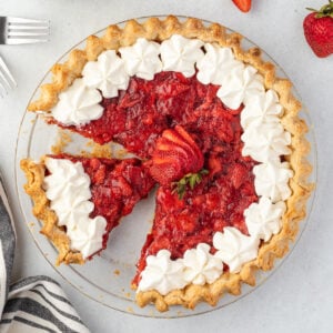 Pie with a slice missin strawberries scattered around.