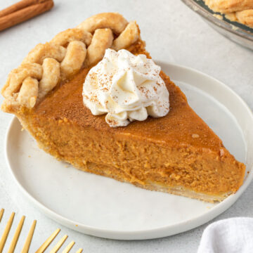 Close up of a slice of pumpkin pie with a dollop of whipped cream.