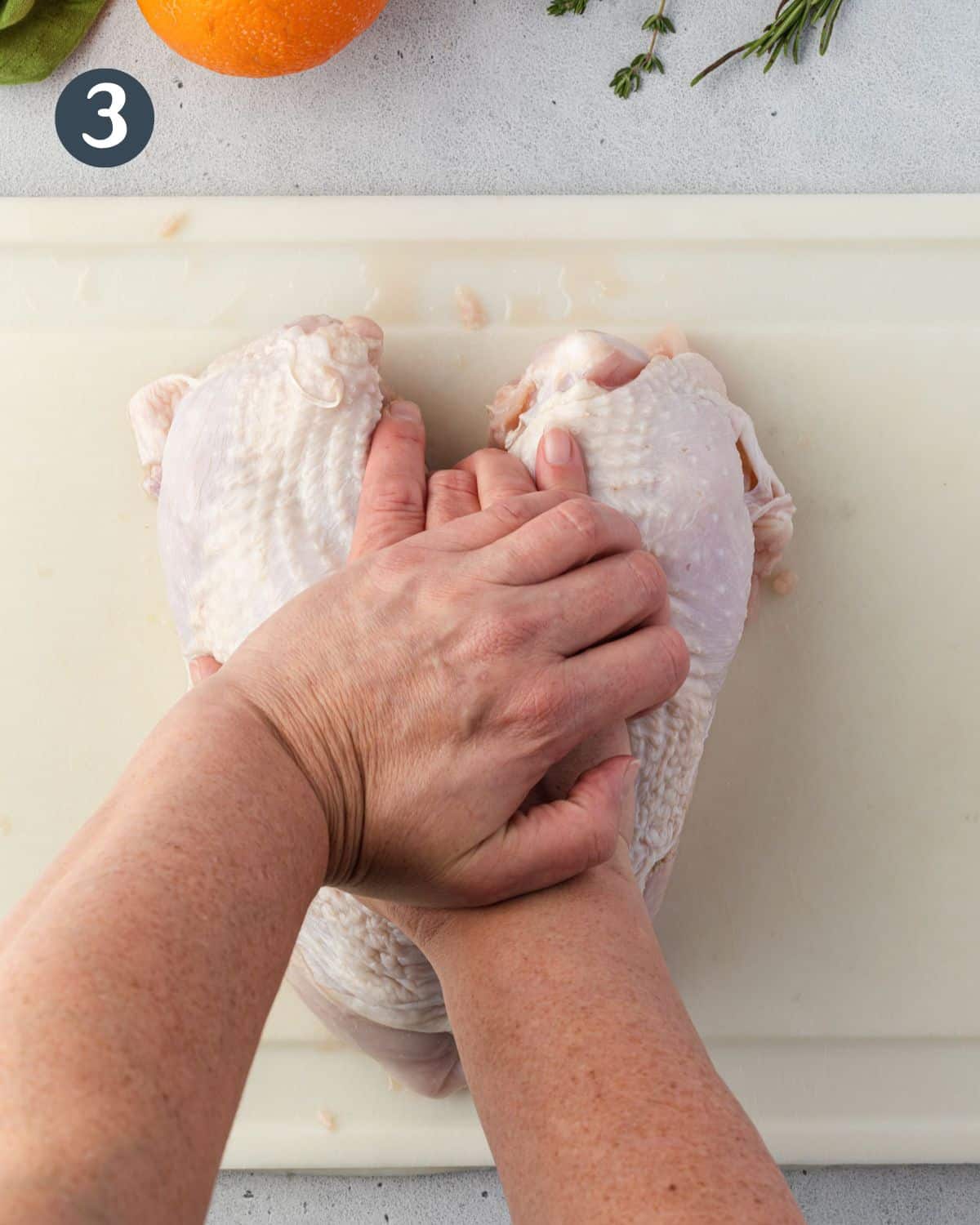 Pressing down on raw turkey breast to crack bone.
