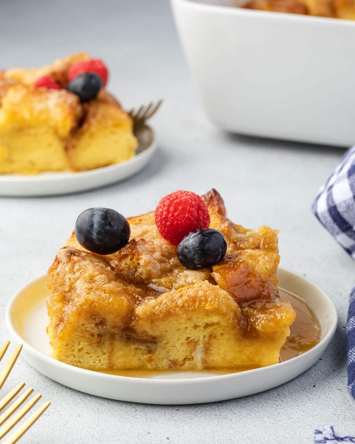 Square of casserole on a plate with berries on top.