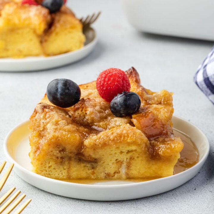 Square of brioche casserole on a plate with berries on top.