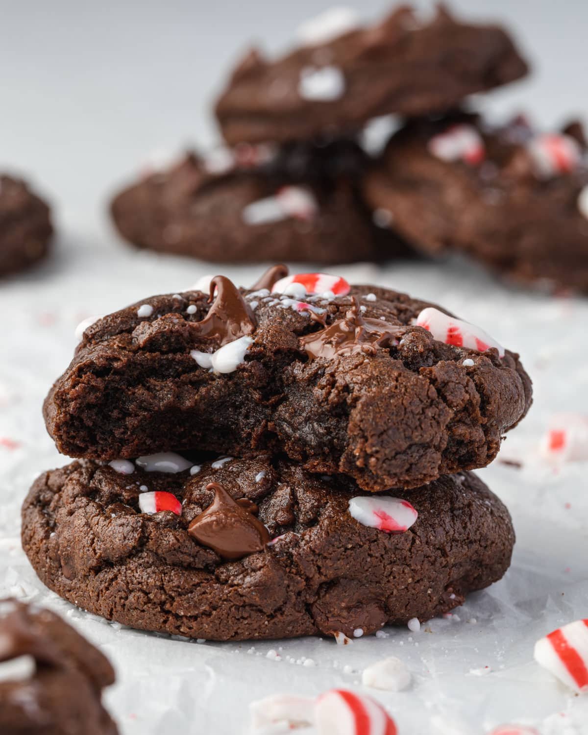 Stacks of double chocolate peppermint cookies, with crushed peppermints and melty chocolate chips.