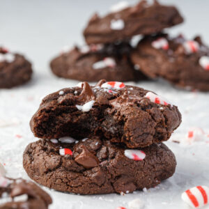 Stacks of double chocolate peppermint cookies, with crushed peppermints and melty chocolate chips.