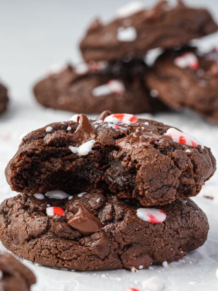 Stacks of double chocolate peppermint cookies, with crushed peppermints and melty chocolate chips.