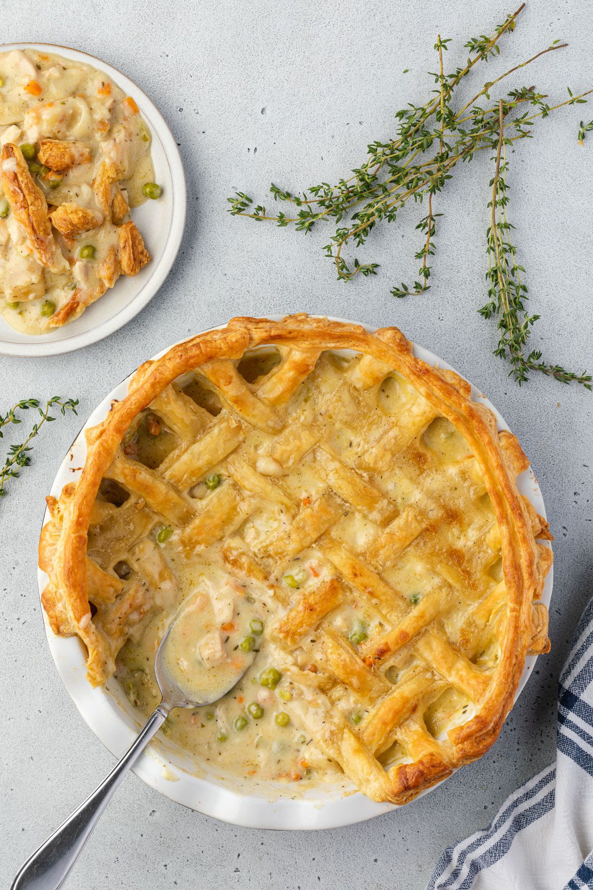 Baked pot pie with a lattice crust and a spoon scooping some out.