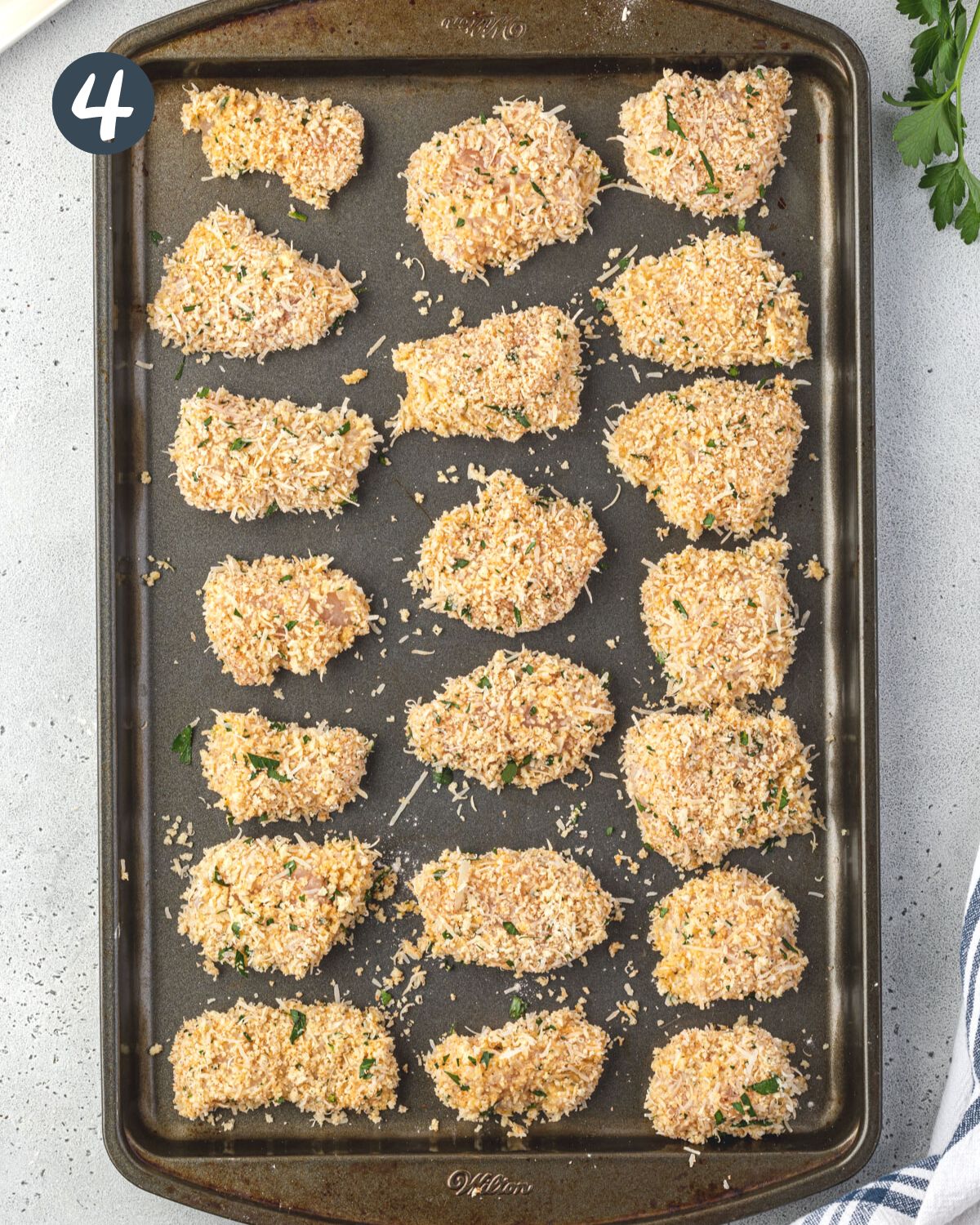 Overhead of boneless wings breaded and on a baking sheet.