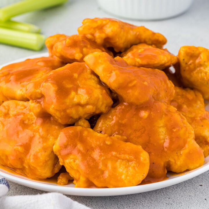 Easy boneless buffalo wings piled in a white plate with celery in background.