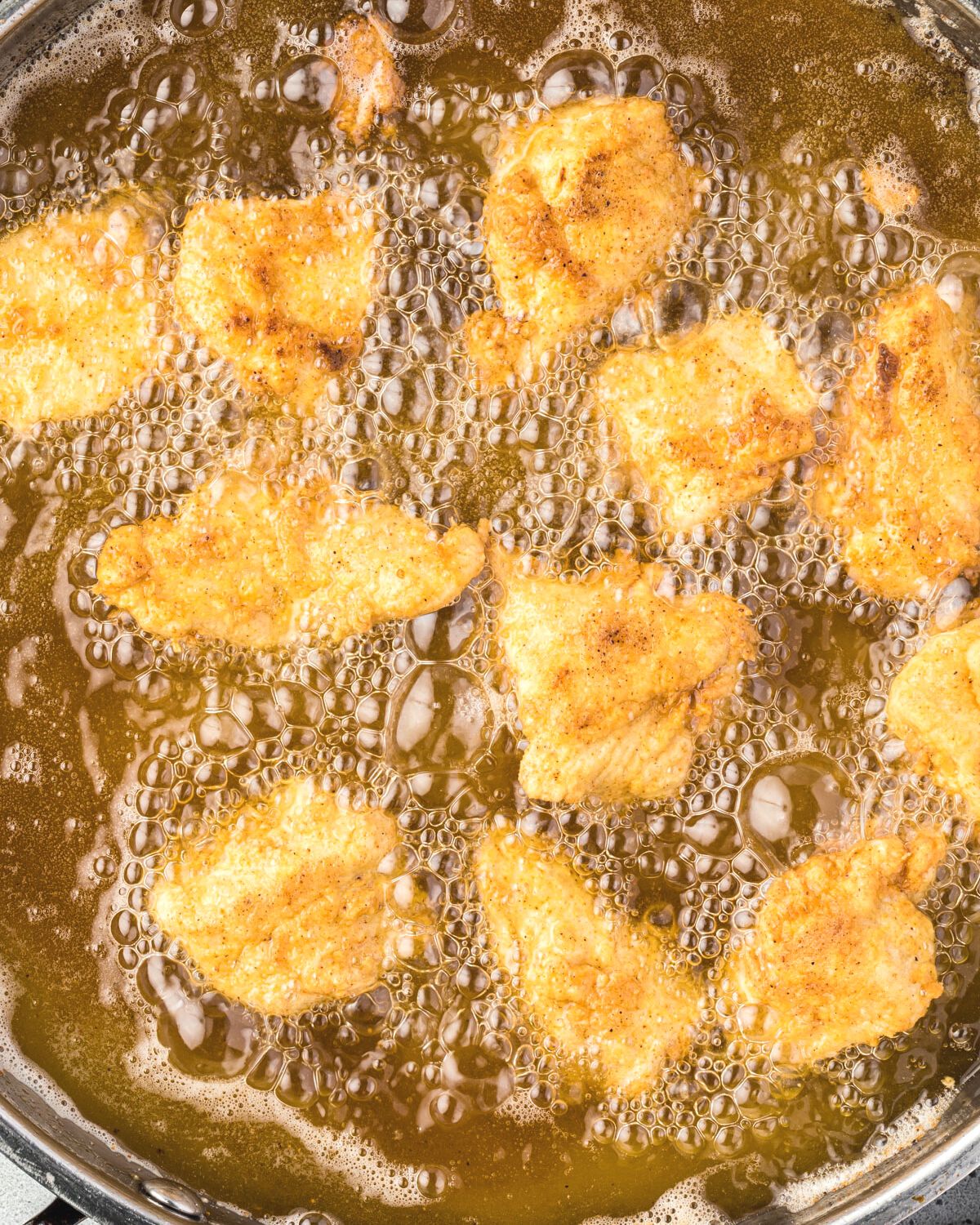 Crispy, golden brown chicken bites in a pan of hot oil.