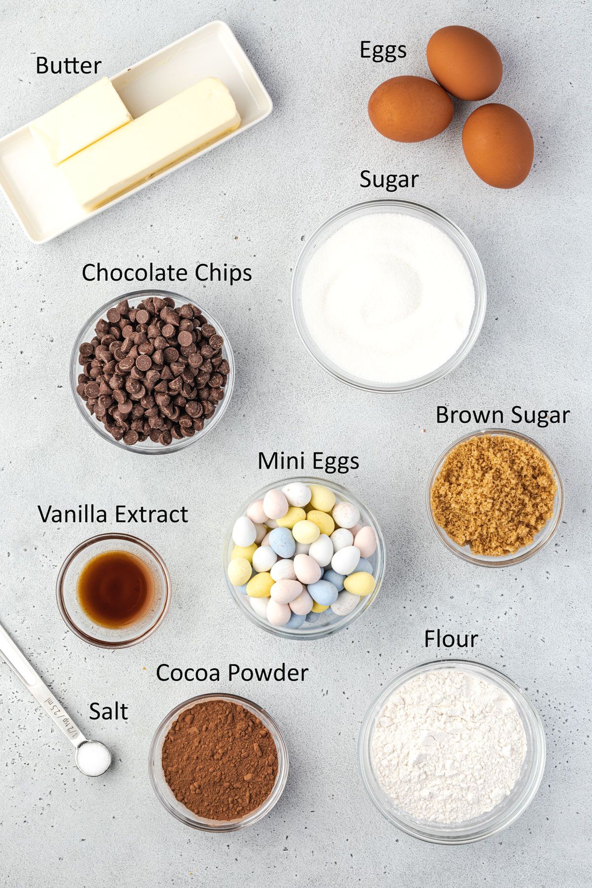 Overhead image showing all of the ingredients for mini egg brownies, measured and in bowls.