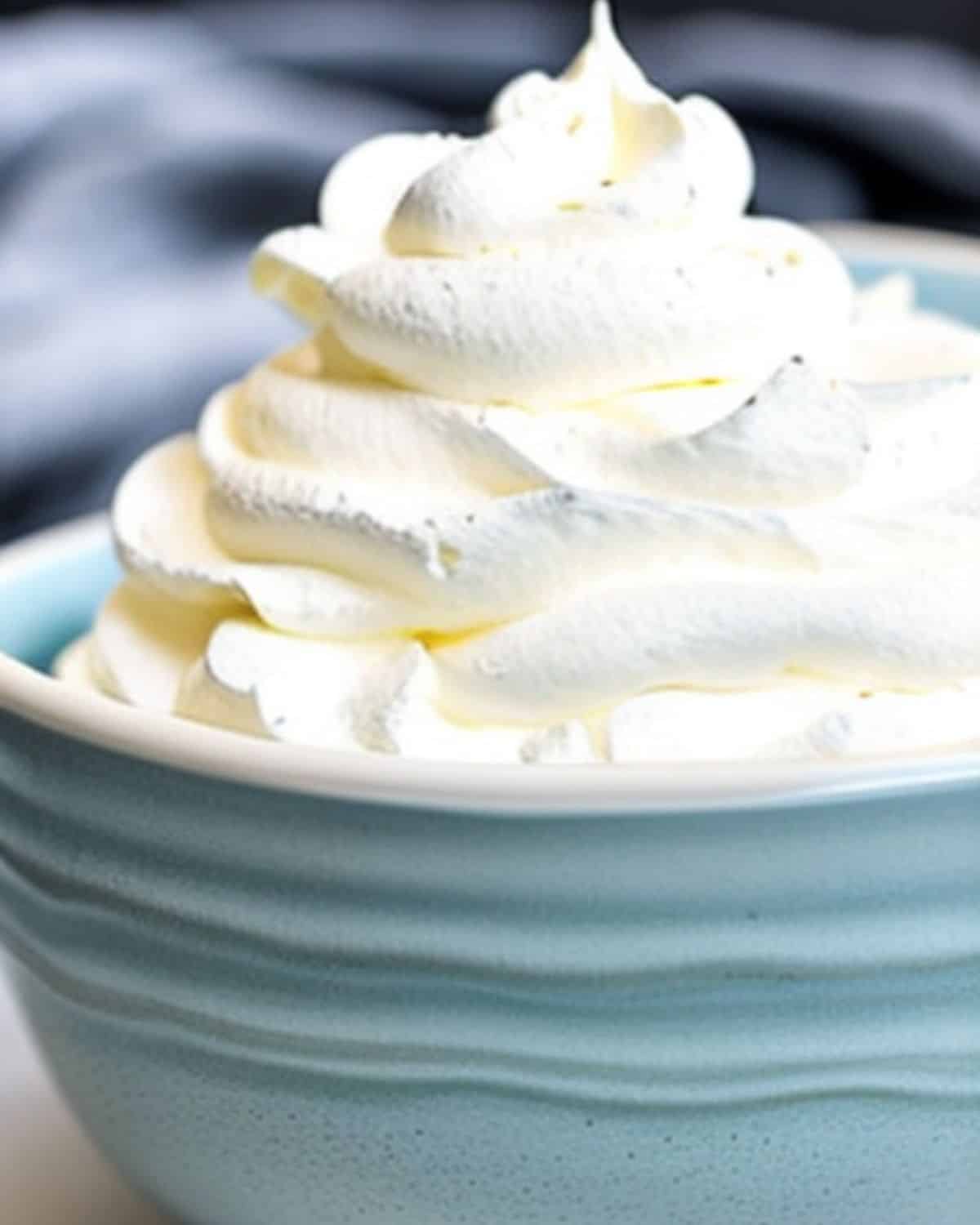 Side view of fluffy whipped cream piled high in a light blue bowl.