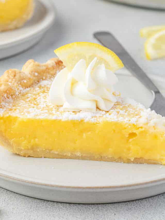 Arizona lemon pie on a plate, topped with whipped cream and a lemon slice, and some lemon slices around it.