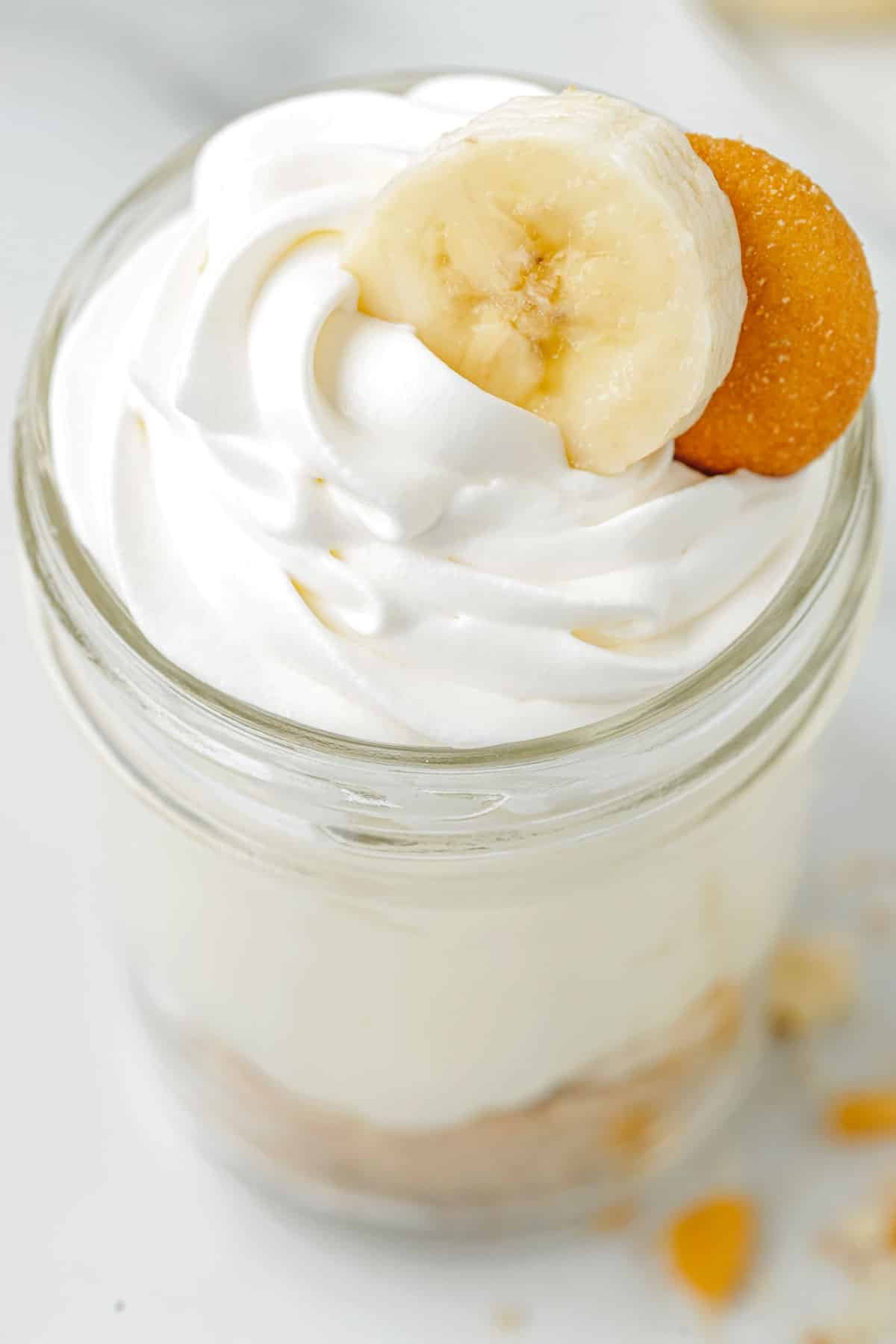 High angle image of a jar of no-bake cheesecake in a jar, focused on whipped cream topping.