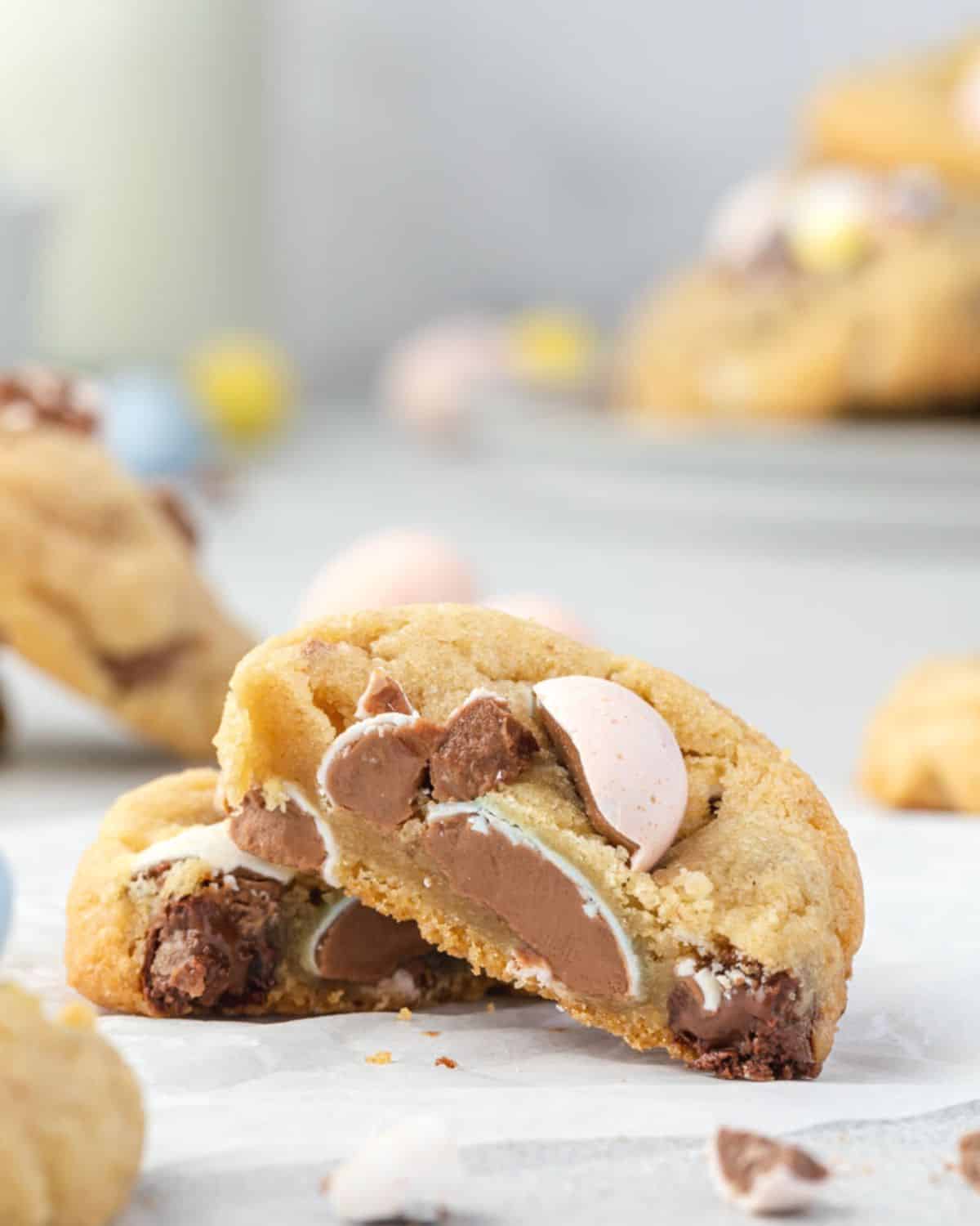 A Cadbury egg cookie cut in half and singled on each other, showing the chunks of chocolate inside the cookie.