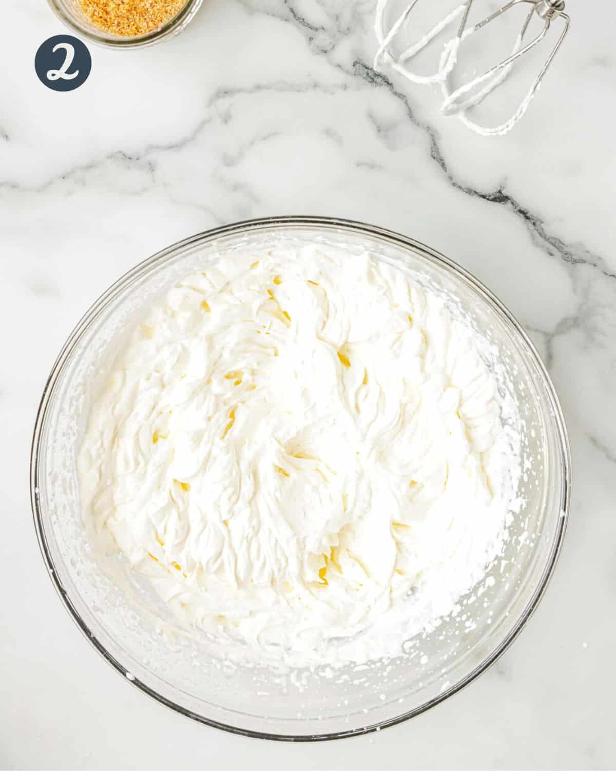 Bowl of fluffy whipped cream in a glass bowl.