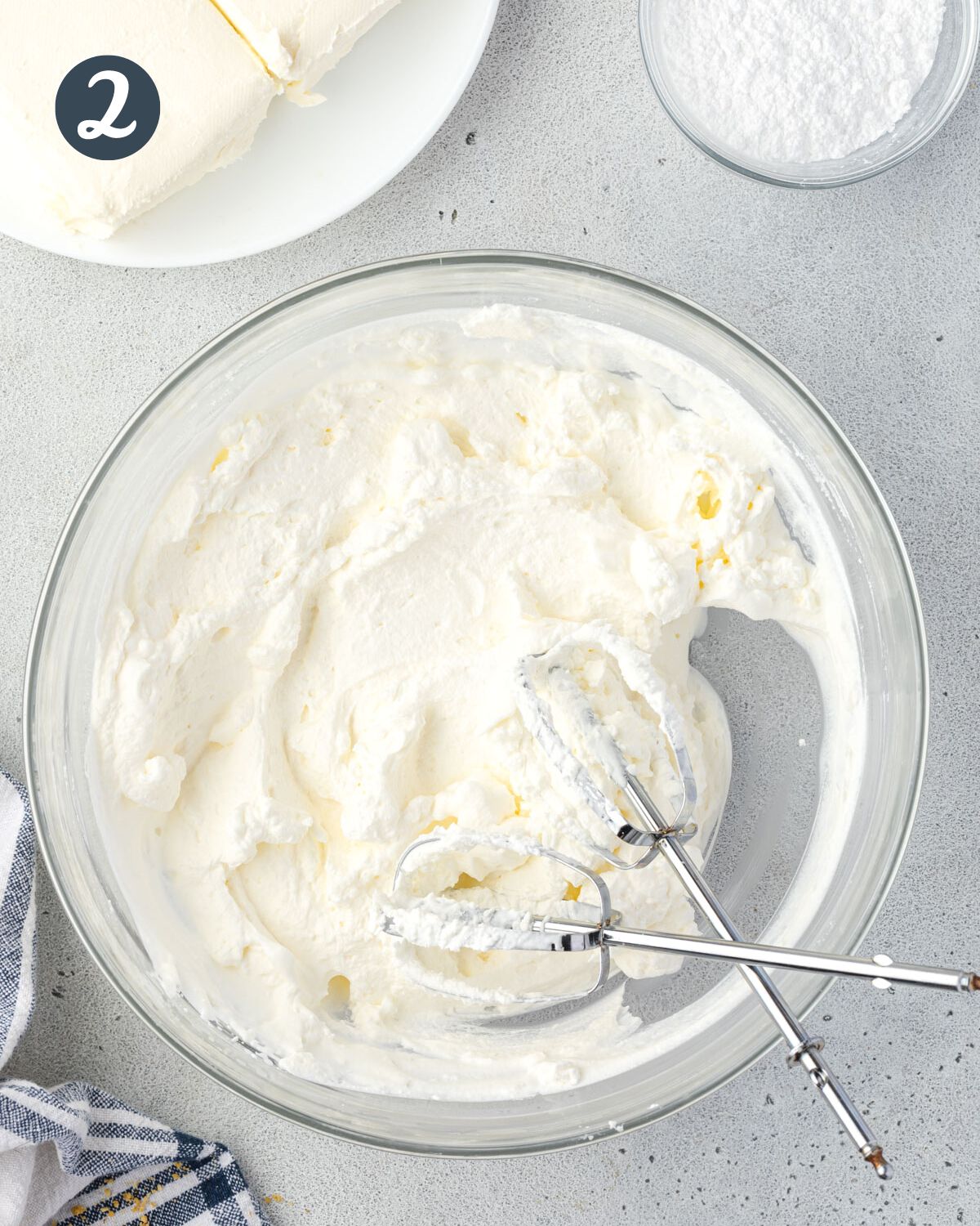 Bowl of whipped cream with beaters criss-crossed in the bowl.