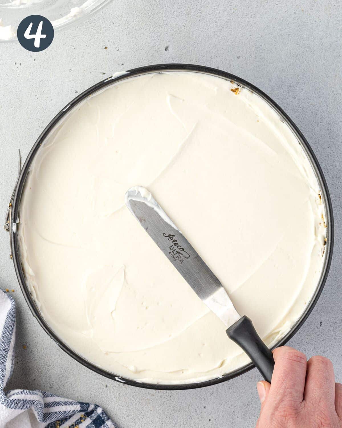 Overhead spreading filling with an offset spatula in a springform pan.