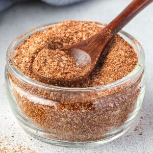 Traditionaltexas brisket rub spice mix in a glass jar with a wooden spoon.