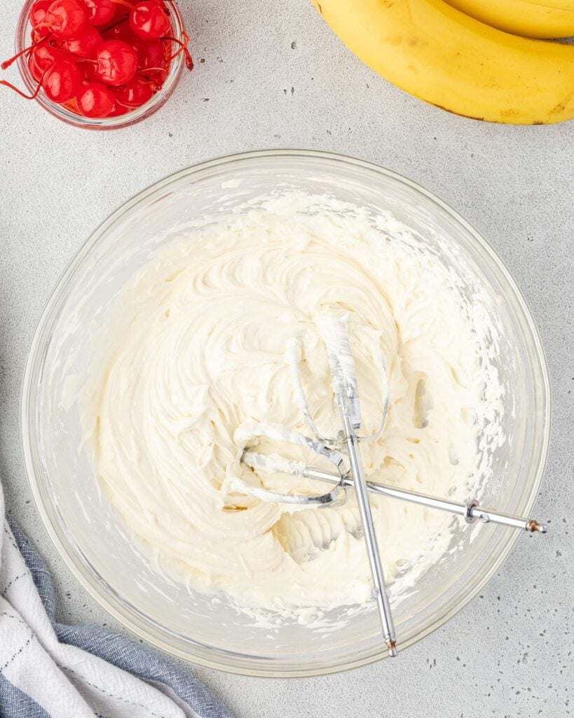 Overhead of a bowl of cream cheese filling with 2 beaters in it.
