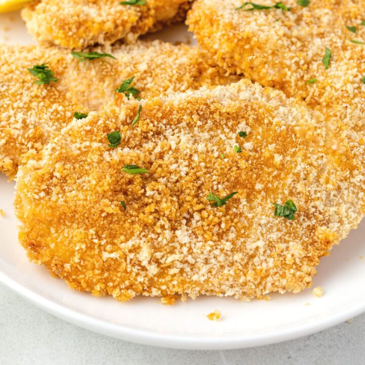 Crispy breaded chicken shingled on a plate sprinkled with parsley.