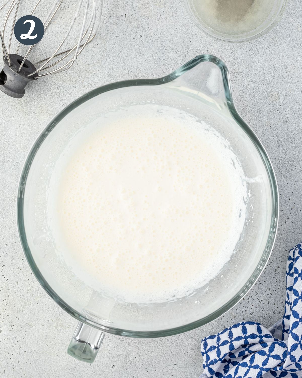 Slightly thickened and foamy dairy in a large glass mixing bowl.