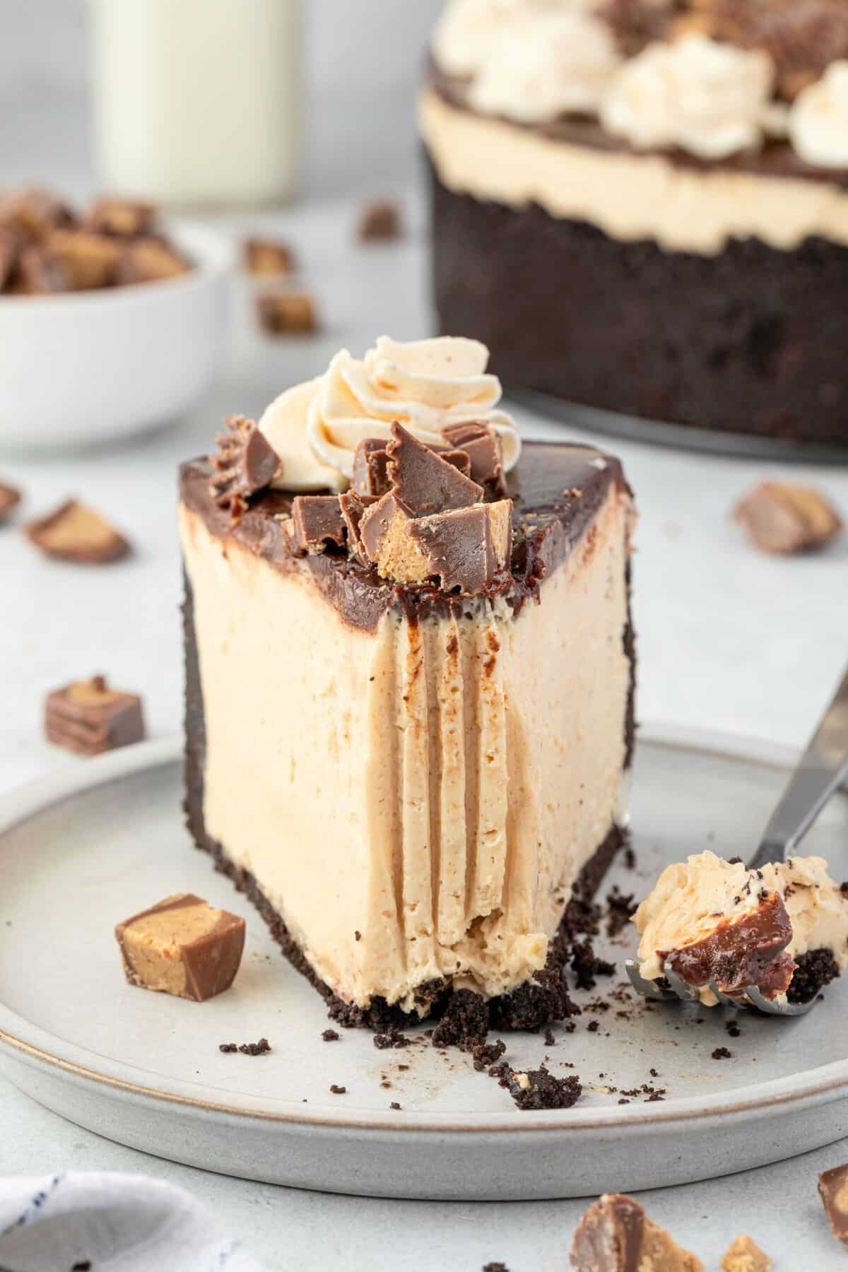 No bake peanut butter cheesecake on a plate with a bite on a fork and the whole cheesecake in the background.