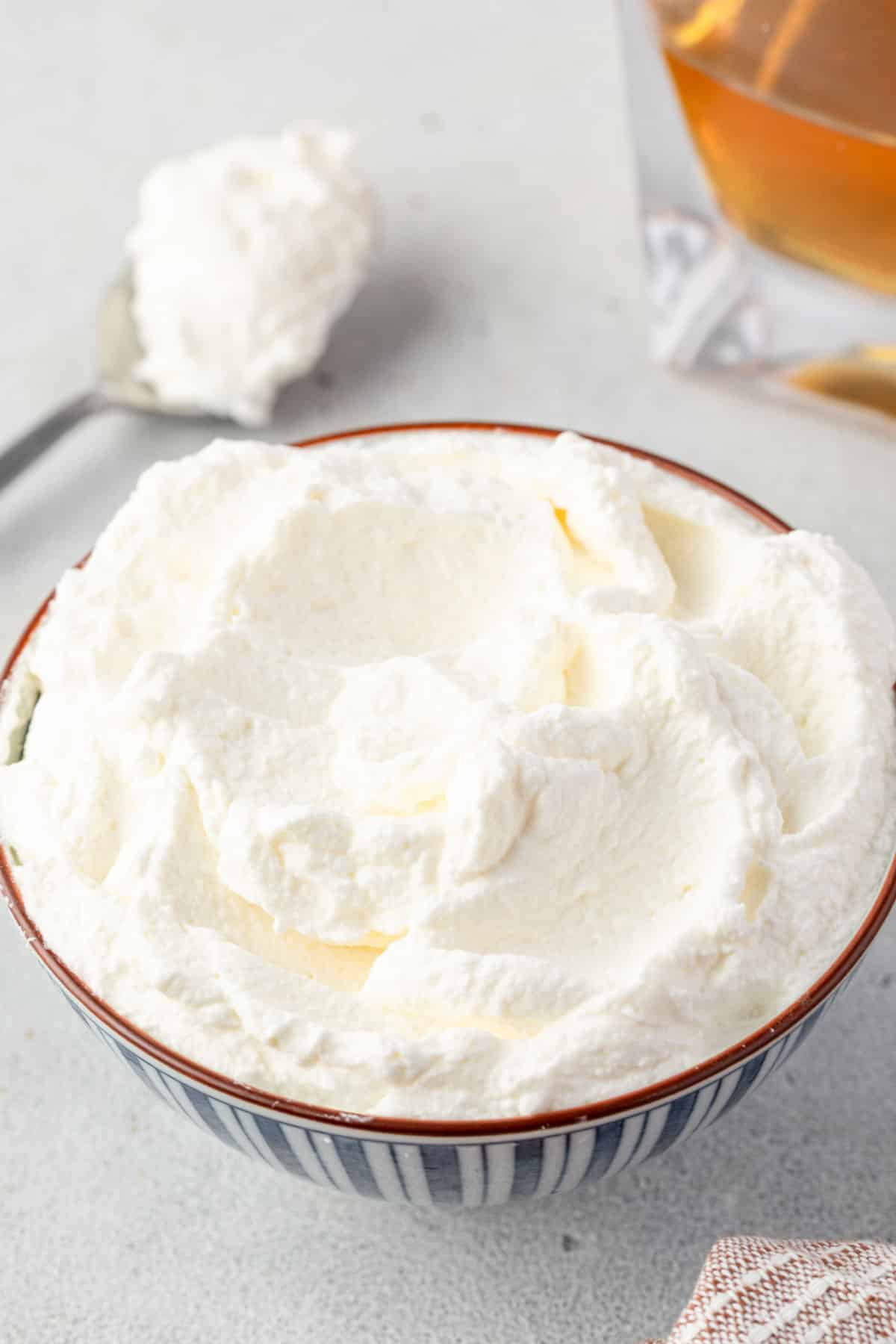 A bowl of whipped cream with divots in it showing that it is firm yet fluffy.