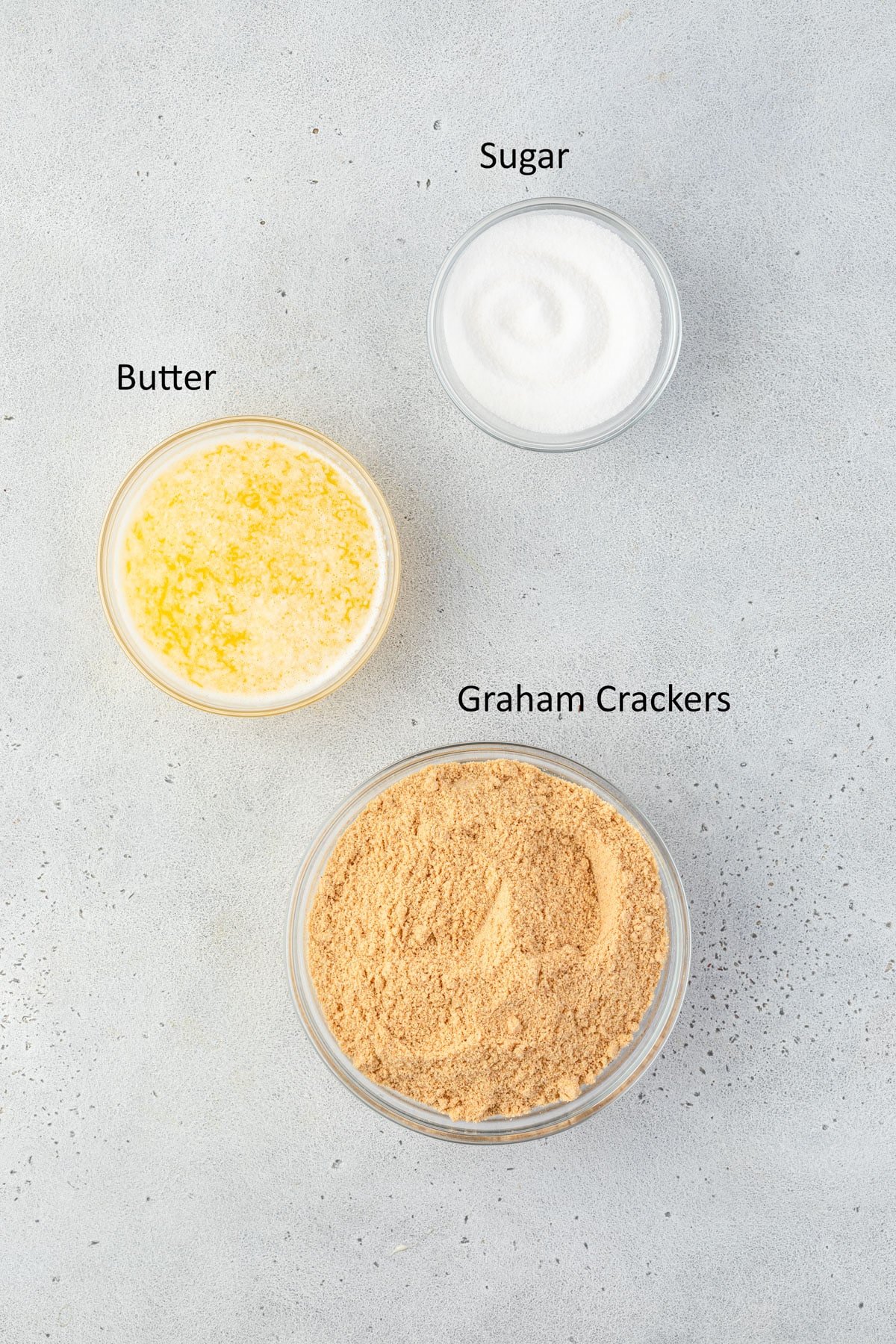 Graham cracker crumbs, granulated sugar, and melted butter in individual bowls.