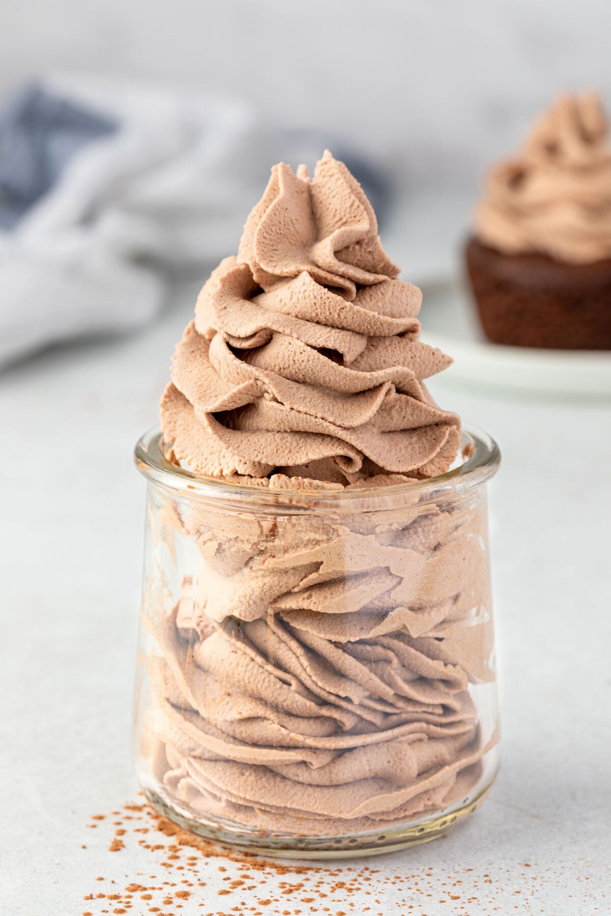 Chocolate whipped cream piped inside a glass jar, with swirls peaking into a point out of the jar.