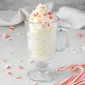Whipped cream in a clear mug, with crushed candy canes sprinkled on top and around.
