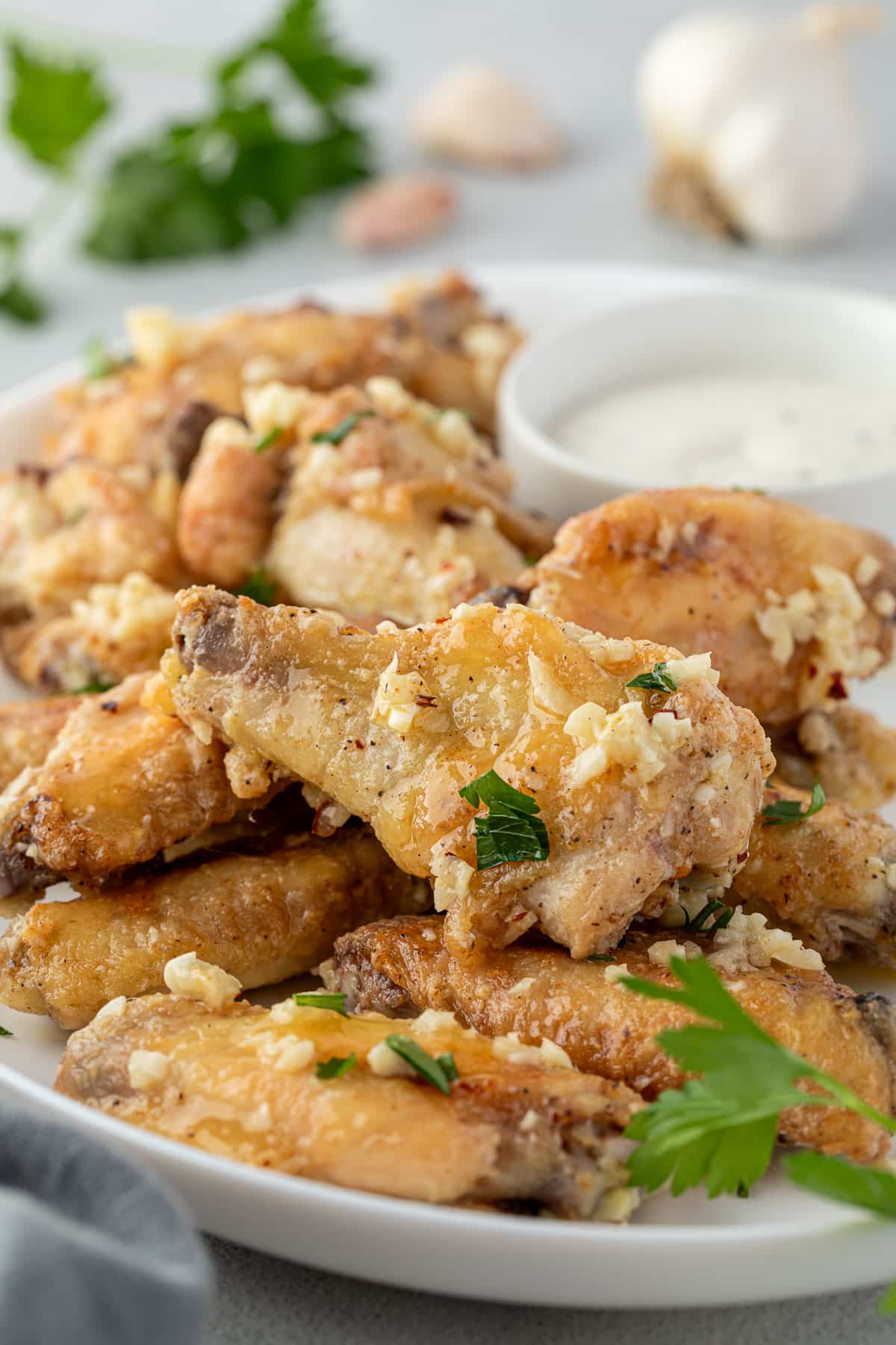 A platter of wings with chopped garlic and parsley on them, an a ramekin of ranch.