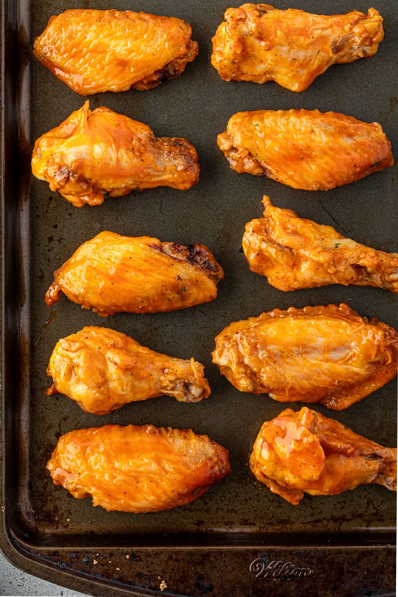 Cooked wings on a dark baking sheet.