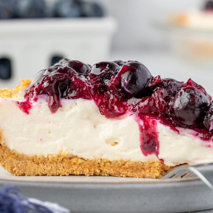 Blueberry cream cheese pie on a plate with a fork resting on it.