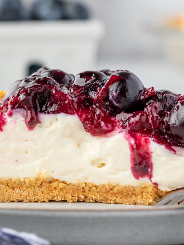 Blueberry cream cheese pie on a plate with a fork resting on it.