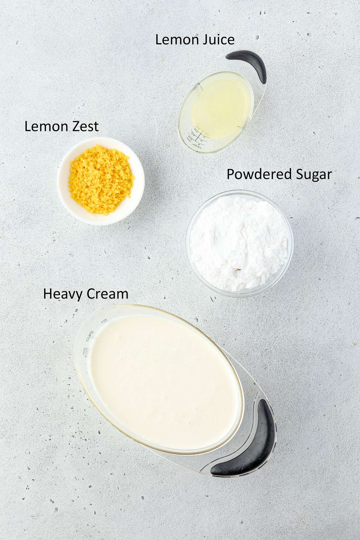 Heavy cream, powdered sugar, lemon zest, and lemon juice in separate containers.