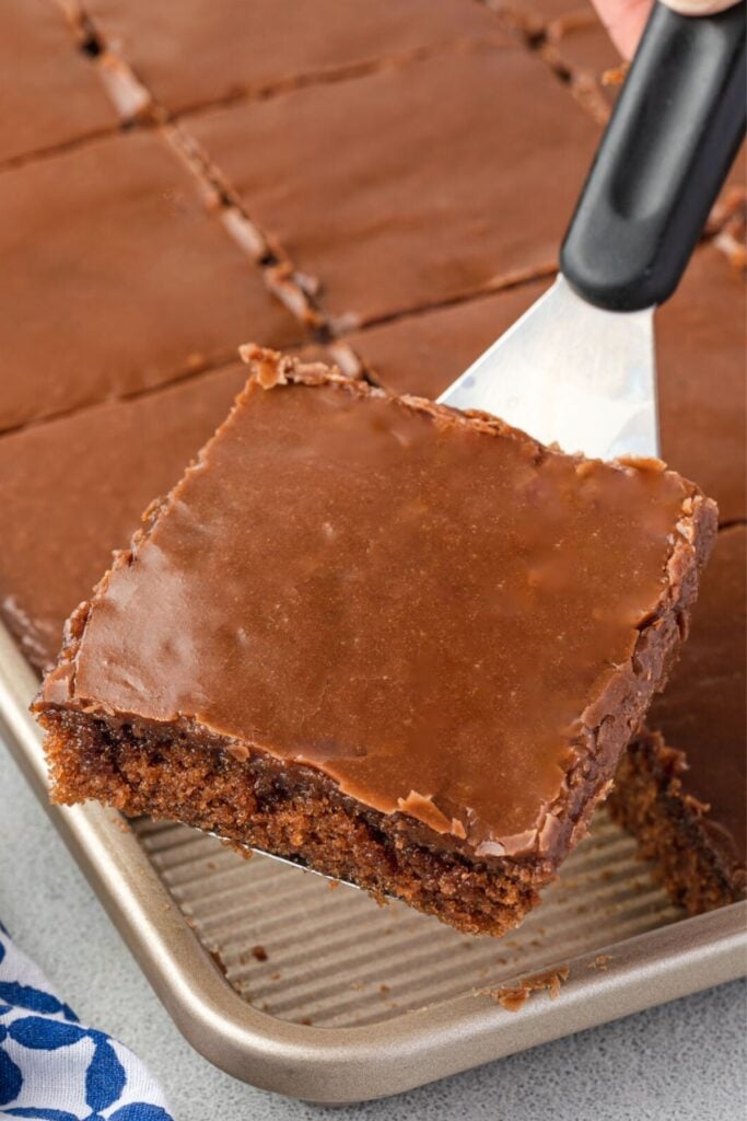 A square of texas sheet cake on a server lifted out of the pan.