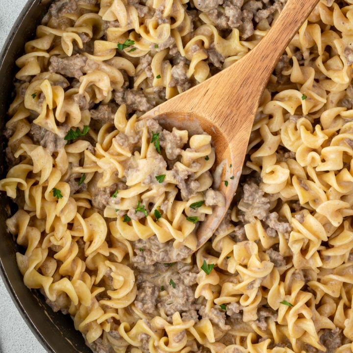 A skillet filled with creamy beef sauce over curly egg noodles.