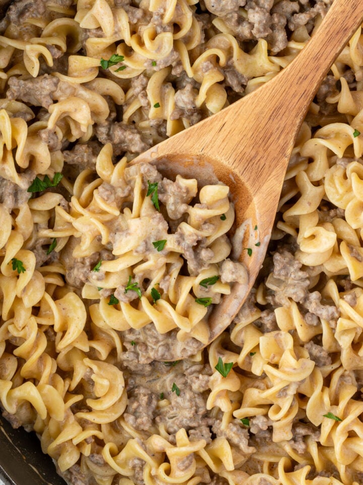 A skillet filled with creamy beef sauce over curly egg noodles.