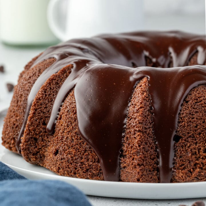 A chocolate Bundt cake , paired perfectly with a glossy chocolate glaze on a white plate.