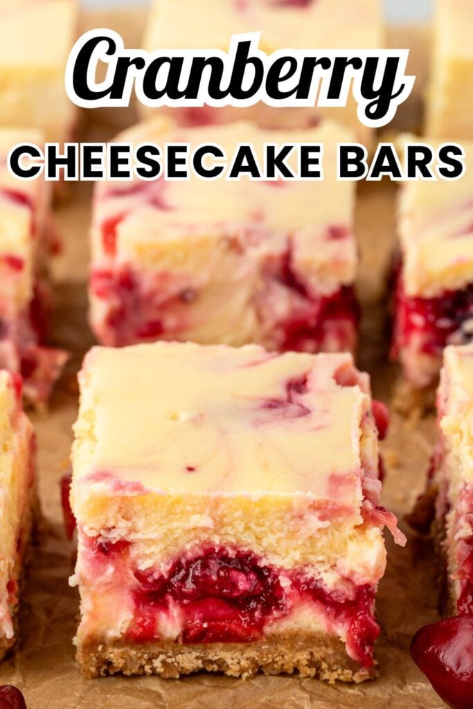 Individual squares of cranberry cheesecake bars on parchment paper.