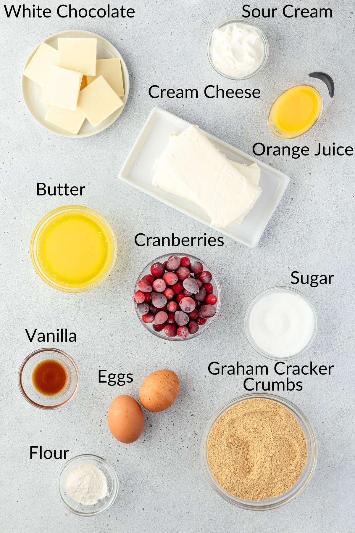 Ingredients for cranberry cheesecake bars arranged on a grey surface.